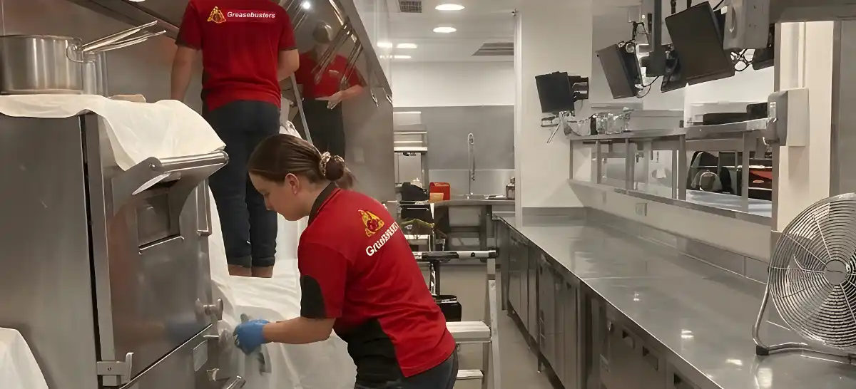 Greasebusters professional technicians deep cleaning a commercial kitchen extract.